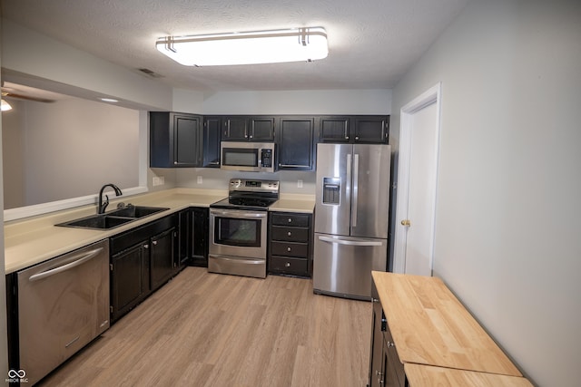 7151 Sea Pine Dr, Indianapolis, IN 46250 - kitchen with stainless steel appliances, light wood-style floors, a textured ceiling, dark cabinetry, and a ceiling fan