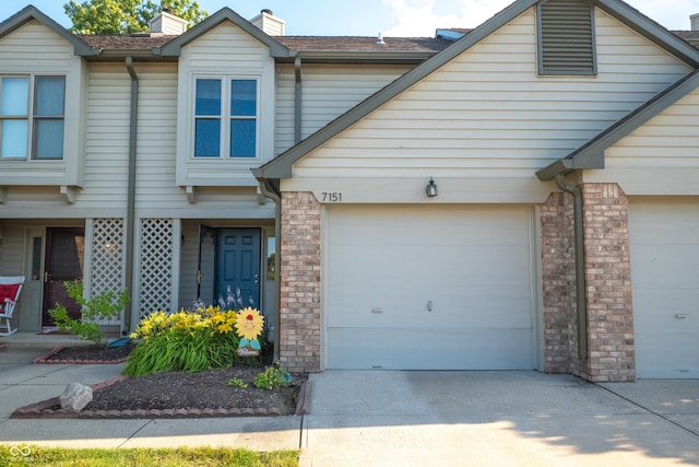 7151 Sea Pine Dr, Indianapolis, IN 46250 - view of property featuring an attached garage, concrete driveway, a chimney, and brick siding