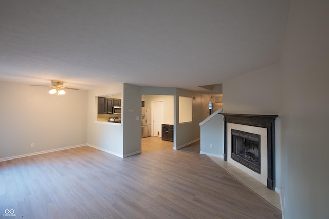7151 Sea Pine Dr, Indianapolis, IN 46250 - unfurnished living room featuring light wood finished floors, a ceiling fan, and a tile fireplace
