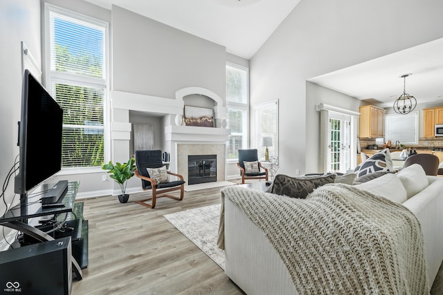 13004 Tuscany Blvd, Carmel, IN 46032 - living area with high vaulted ceiling, a tiled fireplace, light wood-type flooring, and a chandelier
