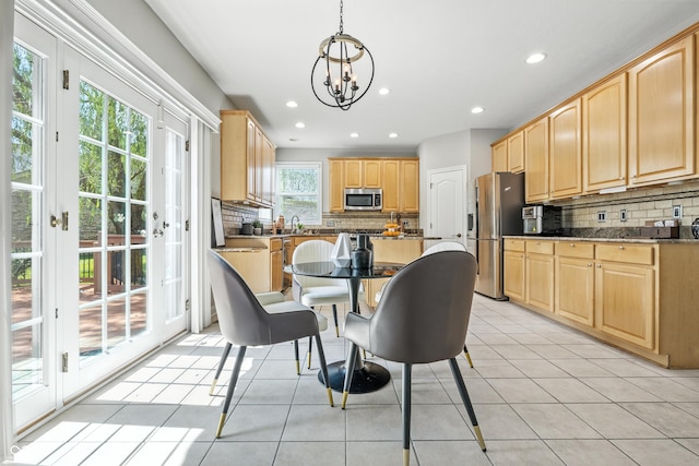 13004 Tuscany Blvd, Carmel, IN 46032 - kitchen featuring appliances with stainless steel finishes, light brown cabinets, tasteful backsplash, a chandelier, and light tile patterned floors