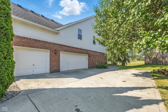 13004 Tuscany Blvd, Carmel, IN 46032 - view of side of home featuring brick siding, driveway, an attached garage, and a shingled roof