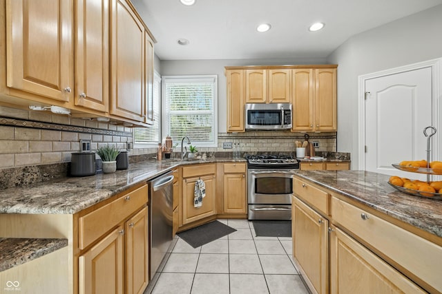 13004 Tuscany Blvd, Carmel, IN 46032 - kitchen featuring appliances with stainless steel finishes, tasteful backsplash, dark stone counters, light tile patterned floors, and recessed lighting