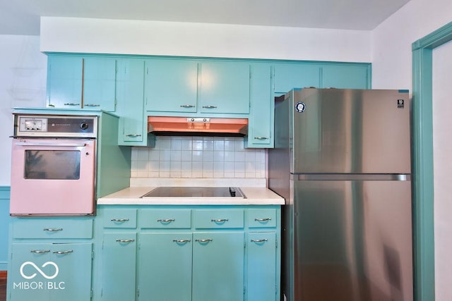 7525 Surrey Dr, Indianapolis, IN 46227 - kitchen featuring freestanding refrigerator, oven, light countertops, black electric cooktop, and backsplash