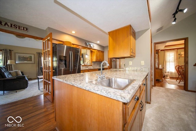 2259 Willow Lake Dr, Greenwood, IN 46143 - kitchen with stainless steel fridge, brown cabinetry, light stone countertops, dark colored carpet, and dark wood-type flooring
