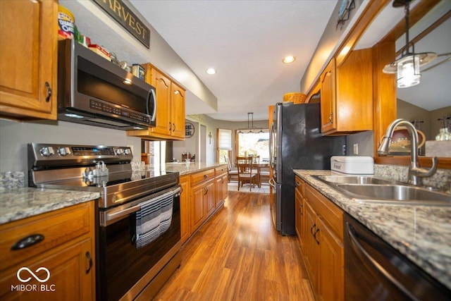 2259 Willow Lake Dr, Greenwood, IN 46143 - kitchen with appliances with stainless steel finishes, brown cabinetry, wood finished floors, pendant lighting, and recessed lighting