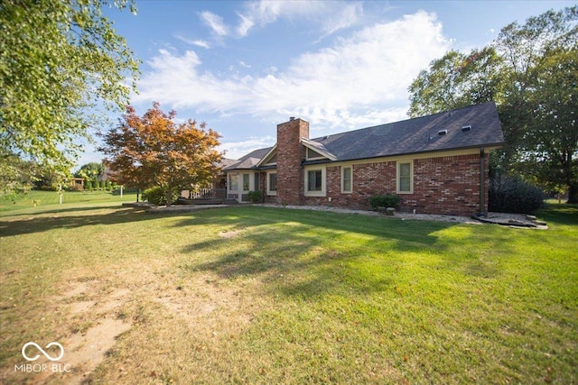 2259 Willow Lake Dr, Greenwood, IN 46143 - back of house featuring brick siding, a chimney, and a lawn