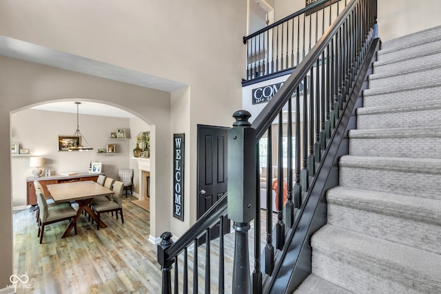 5961 Pine Bluff Dr, Avon, IN 46123 - staircase with wood finished floors, arched walkways, and a towering ceiling