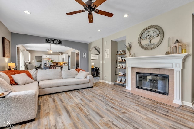 5961 Pine Bluff Dr, Avon, IN 46123 - living room featuring arched walkways, light wood finished floors, ceiling fan, recessed lighting, and a fireplace