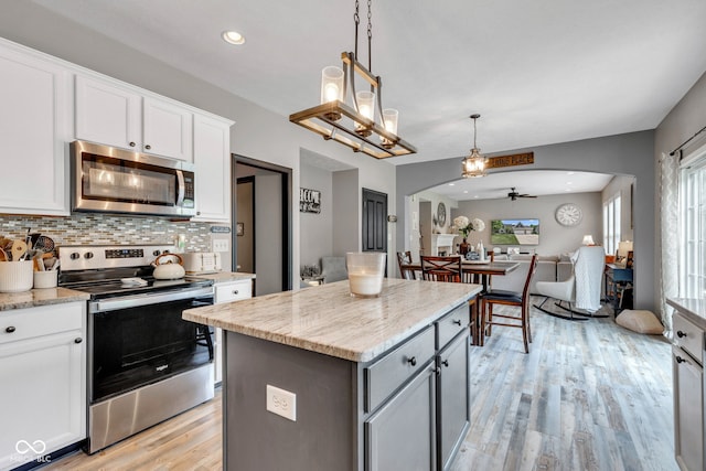 5961 Pine Bluff Dr, Avon, IN 46123 - kitchen with stainless steel appliances, arched walkways, open floor plan, ceiling fan, and light wood-style flooring