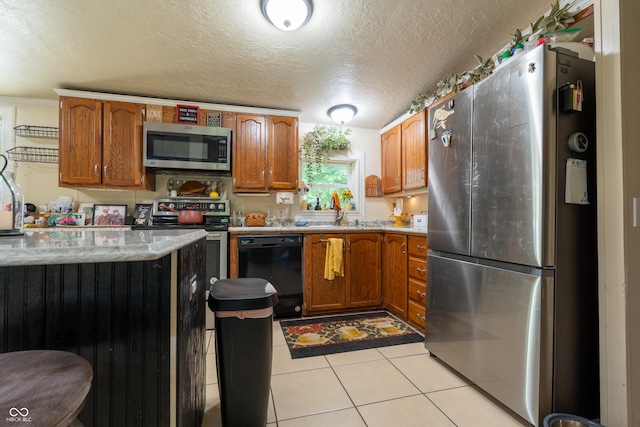 2501 Mitten Rd, Bowling Green, IN 47833 - kitchen featuring appliances with stainless steel finishes, a textured ceiling, brown cabinetry, light tile patterned floors, and light stone countertops