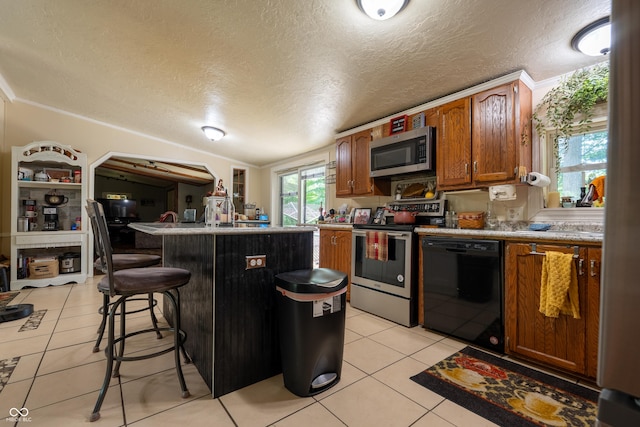 2501 Mitten Rd, Bowling Green, IN 47833 - kitchen featuring stainless steel appliances, light tile patterned flooring, a textured ceiling, a kitchen breakfast bar, and brown cabinetry