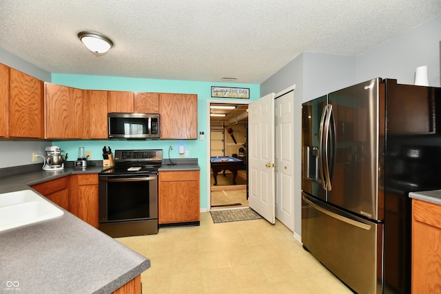 2016 Morning Light Ln, Greenwood, IN 46143 - kitchen featuring stainless steel appliances, brown cabinets, a textured ceiling, light floors, and dark countertops