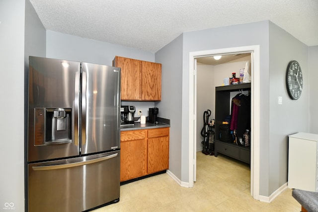 2016 Morning Light Ln, Greenwood, IN 46143 - kitchen featuring stainless steel fridge, brown cabinetry, a textured ceiling, and dark countertops