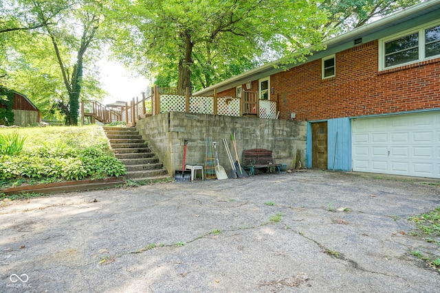 4720 Kessler View Dr, Indianapolis, IN 46220 - view of side of property with brick siding, an attached garage, asphalt driveway, and stairway