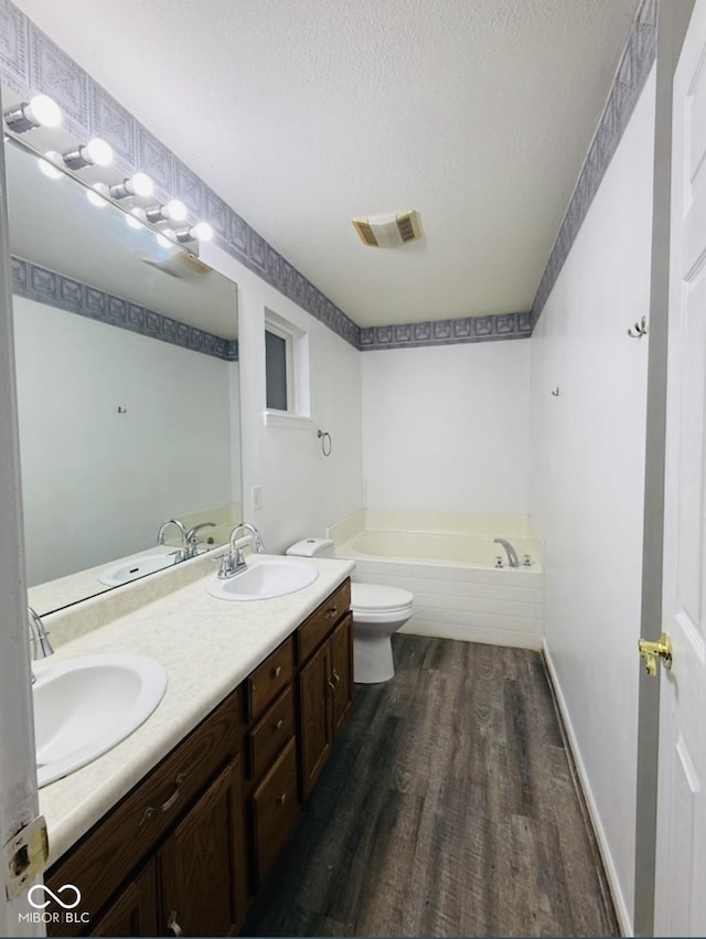 19519 Prairie Crossing Dr, Noblesville, IN 46062 - bathroom with wood finished floors, a garden tub, double vanity, and a textured ceiling