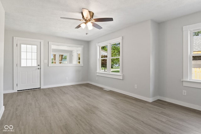 135 S Dr, Anderson, IN 46013 - unfurnished living room featuring wood finished floors, plenty of natural light, a ceiling fan, and a textured ceiling