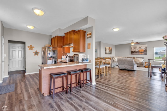 1397 Greenbriar Way, Franklin, IN 46131 - kitchen featuring appliances with stainless steel finishes, under cabinet range hood, brown cabinetry, dark wood finished floors, and light countertops