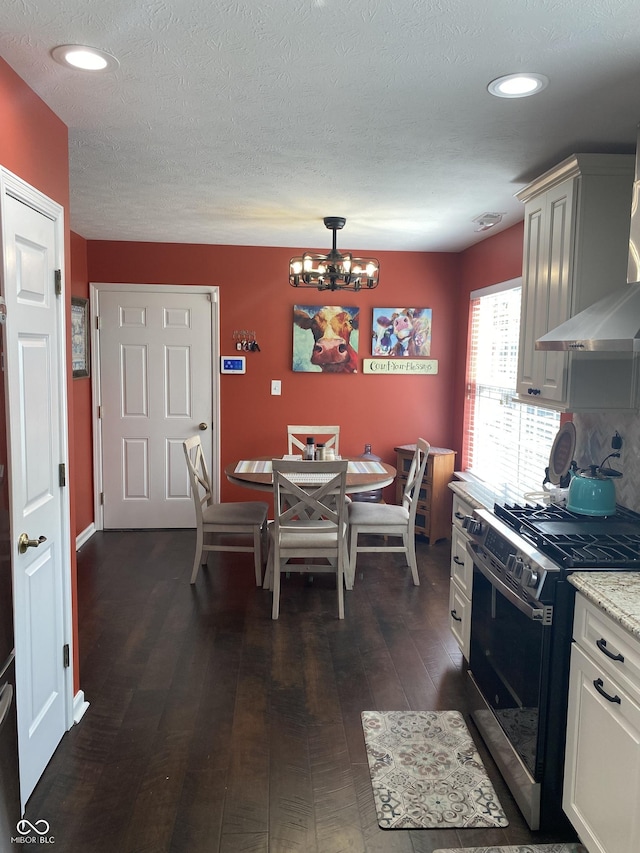 1675 Leisure Way, Greenfield, IN 46140 - kitchen featuring black range with gas stovetop, a chandelier, dark wood-style flooring, a textured ceiling, and wall chimney exhaust hood