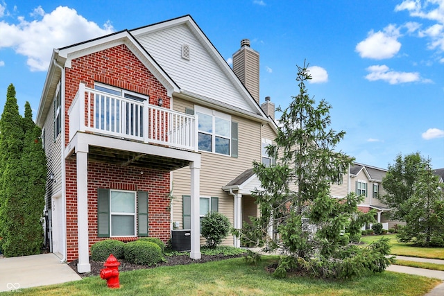 13225 Deception Pass Unit 700, Fishers, IN 46038 - view of front of house featuring a balcony, brick siding, a chimney, and a front yard