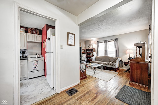 1810 Calhoun St, Indianapolis, IN 46203 - kitchen featuring white appliances, open floor plan, light wood-style floors, and a textured ceiling