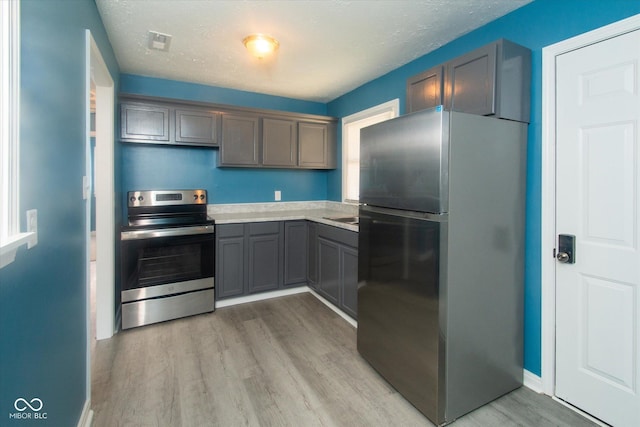 8047 E 48th St, Indianapolis, IN 46226 - kitchen with freestanding refrigerator, stainless steel range with electric cooktop, gray cabinets, light wood-type flooring, and light countertops