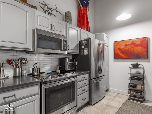 430 N Park Ave Unit 104, Indianapolis, IN 46202 - kitchen featuring stainless steel appliances, dark countertops, decorative backsplash, light tile patterned floors, and white cabinetry