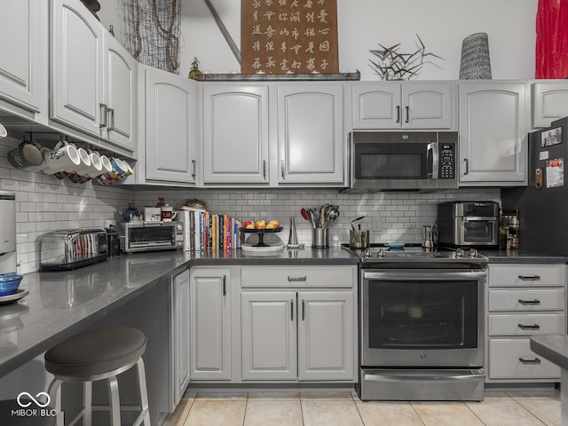 430 N Park Ave Unit 104, Indianapolis, IN 46202 - kitchen with stainless steel appliances, decorative backsplash, light tile patterned flooring, and white cabinets