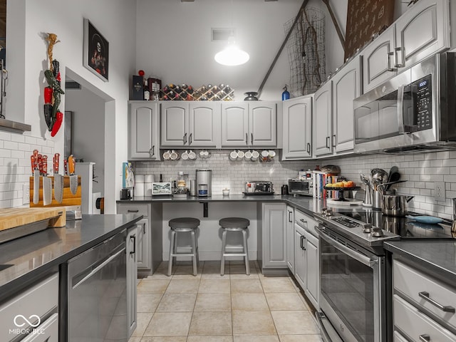 430 N Park Ave Unit 104, Indianapolis, IN 46202 - kitchen featuring stainless steel appliances, dark countertops, decorative backsplash, and light tile patterned floors