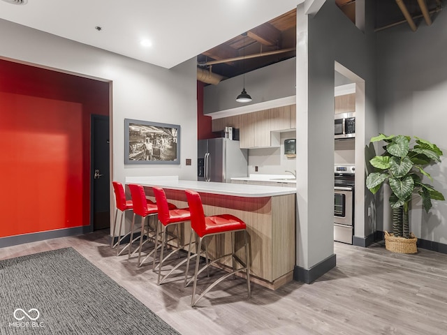 430 N Park Ave Unit 104, Indianapolis, IN 46202 - kitchen with stainless steel appliances, a breakfast bar, light wood finished floors, light countertops, and decorative light fixtures