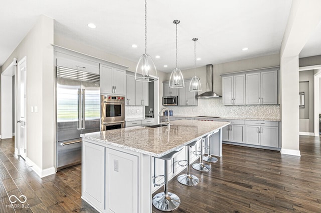 14293 Dufton Ct, Carmel, IN 46074 - kitchen featuring appliances with stainless steel finishes, wall chimney range hood, backsplash, a kitchen bar, and an island with sink