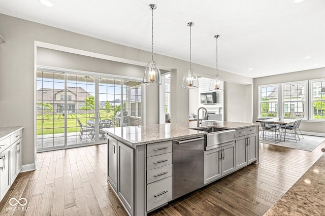 14293 Dufton Ct, Carmel, IN 46074 - kitchen with stainless steel dishwasher, gray cabinetry, dark wood-type flooring, light stone countertops, and a center island with sink