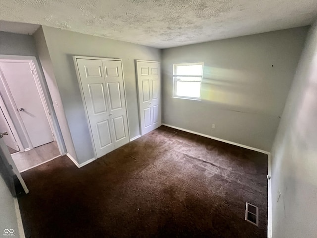 3525 Luewan Ct, Indianapolis, IN 46235 - unfurnished bedroom with two closets, dark carpet, and a textured ceiling