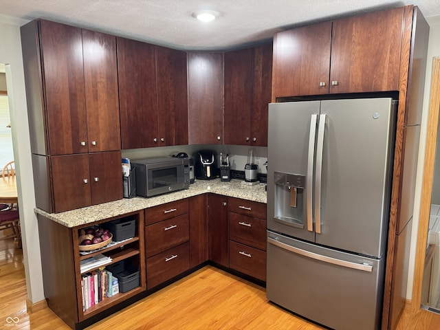 1220 Countryside Ln, Columbus, IN 47201 - kitchen featuring appliances with stainless steel finishes, light wood-type flooring, light stone counters, a textured ceiling, and dark brown cabinetry