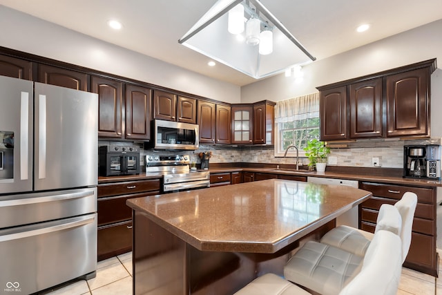 2847 Macintosh, Columbus, IN 47201 - kitchen with stainless steel appliances, a kitchen breakfast bar, dark brown cabinetry, light tile patterned flooring, and tasteful backsplash