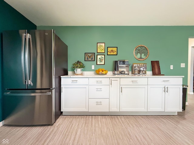 8883 W Hilltop Ln, Elwood, IN 46036 - kitchen with freestanding refrigerator, light wood finished floors, white cabinets, and light countertops