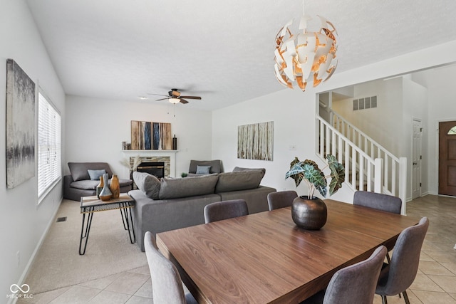 10792 Sawgrass Dr, Fishers, IN 46037 - dining room with light tile patterned floors, stairway, ceiling fan, and a fireplace