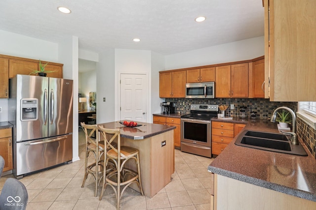 10792 Sawgrass Dr, Fishers, IN 46037 - kitchen with appliances with stainless steel finishes, dark countertops, a center island, decorative backsplash, and a kitchen breakfast bar