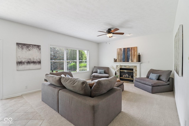 10792 Sawgrass Dr, Fishers, IN 46037 - living room with light carpet, ceiling fan, a stone fireplace, light tile patterned floors, and a textured ceiling