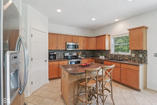 10792 Sawgrass Dr, Fishers, IN 46037 - kitchen featuring appliances with stainless steel finishes, dark countertops, a kitchen island, backsplash, and light tile patterned floors