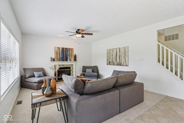 10792 Sawgrass Dr, Fishers, IN 46037 - living area with light carpet, ceiling fan, a stone fireplace, light tile patterned floors, and stairs