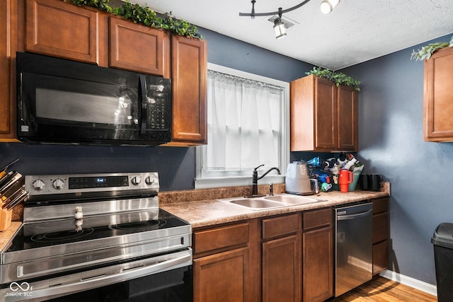 43 W Main St, North Vernon, IN 47265 - kitchen with stainless steel appliances, light wood-style floors, brown cabinetry, and a textured ceiling
