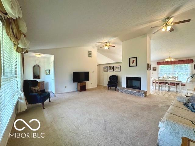1042 W Oak Hill Xing, Crawfordsville, IN 47933 - carpeted living room with a glass covered fireplace, ceiling fan, and vaulted ceiling
