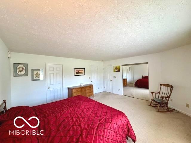 1042 W Oak Hill Xing, Crawfordsville, IN 47933 - carpeted bedroom with a textured ceiling and two closets