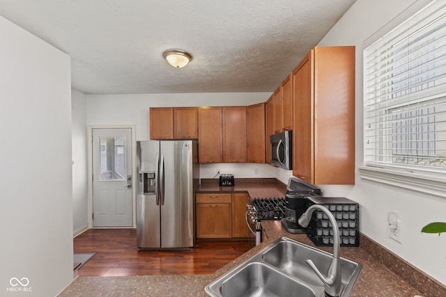 2232 N Park Ave, Indianapolis, IN 46205 - kitchen with stainless steel appliances, brown cabinets, dark countertops, dark wood finished floors, and a textured ceiling