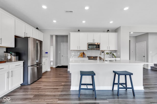 9978 Trafford Ct, Mccordsville, IN 46055 - kitchen featuring appliances with stainless steel finishes, dark wood finished floors, decorative backsplash, white cabinets, and recessed lighting