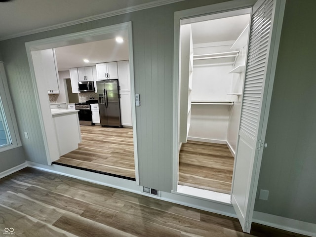 84 S Schenck Rd, Crawfordsville, IN 47933 - kitchen with stainless steel appliances, wood finished floors, white cabinets, crown molding, and light countertops