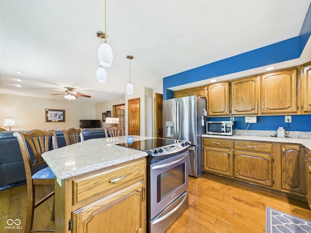 1014 Gray Squirrel Dr, Pendleton, IN 46064 - kitchen with stainless steel appliances, light wood-style flooring, open floor plan, a ceiling fan, and decorative light fixtures