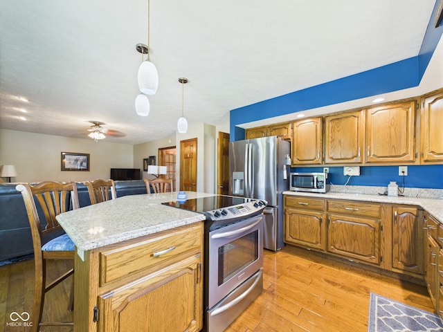 1014 Gray Squirrel Dr, Pendleton, IN 46064 - kitchen with stainless steel appliances, light wood finished floors, ceiling fan, hanging light fixtures, and open floor plan