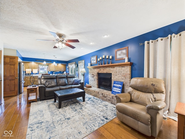 1014 Gray Squirrel Dr, Pendleton, IN 46064 - living room featuring ceiling fan, hardwood / wood-style flooring, a brick fireplace, a textured ceiling, and recessed lighting